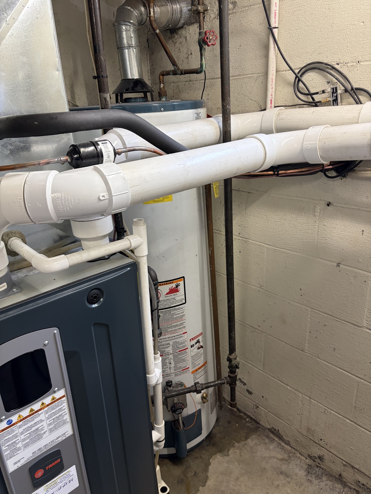 Water heater and furnace installation with new PVC and copper piping in a basement mechanical room